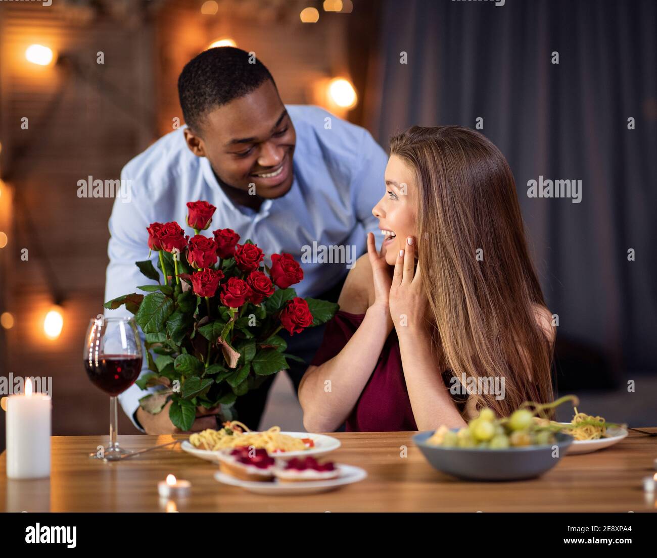 Valentinstag Überraschung. Elegant African Man Giving Roses To Freundin Im Restaurant Stockfoto
