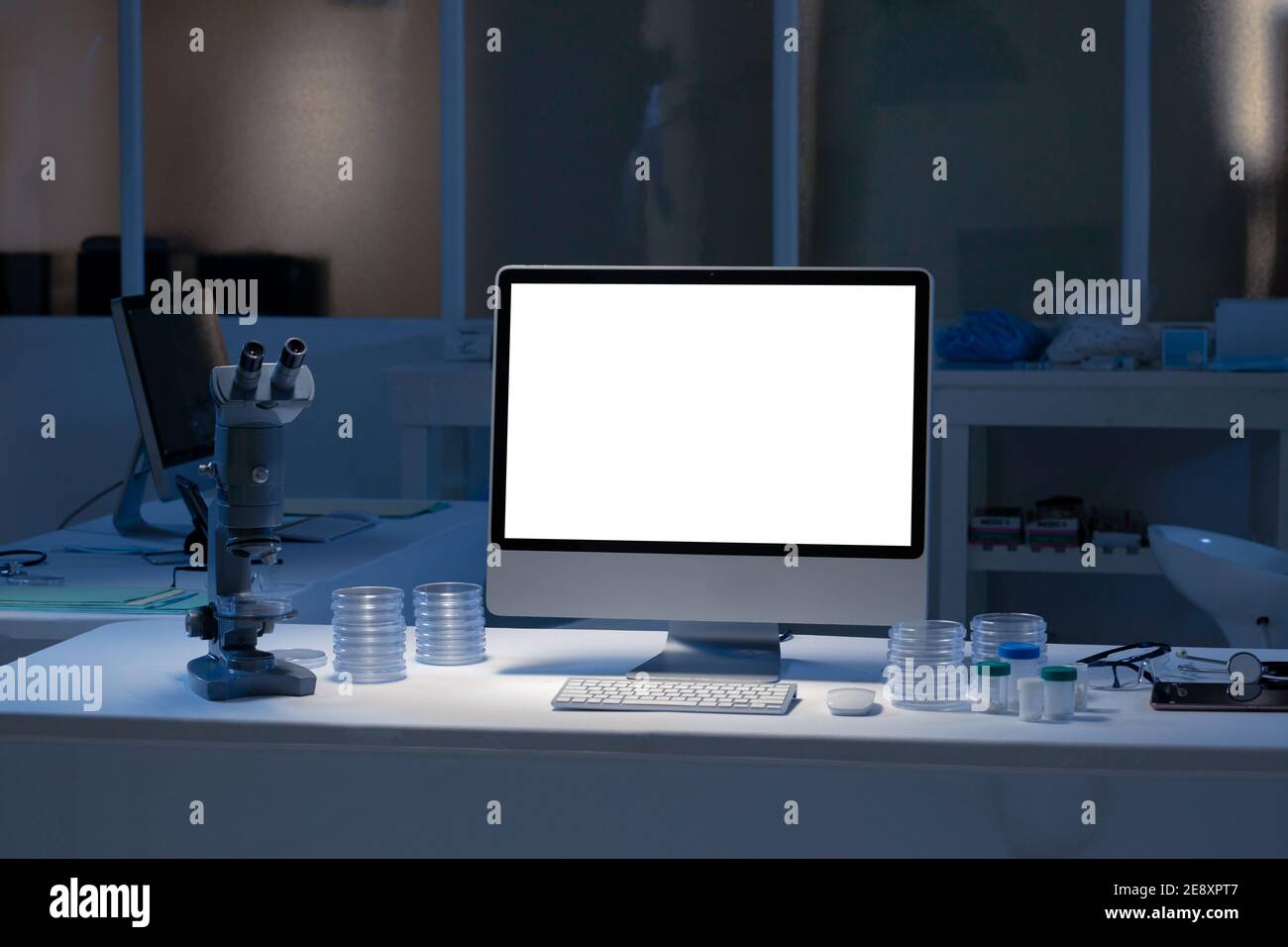 Desktop-Computer mit beleuchtetem Bildschirm am Arbeitsplatz im medizinischen Labor Stockfoto