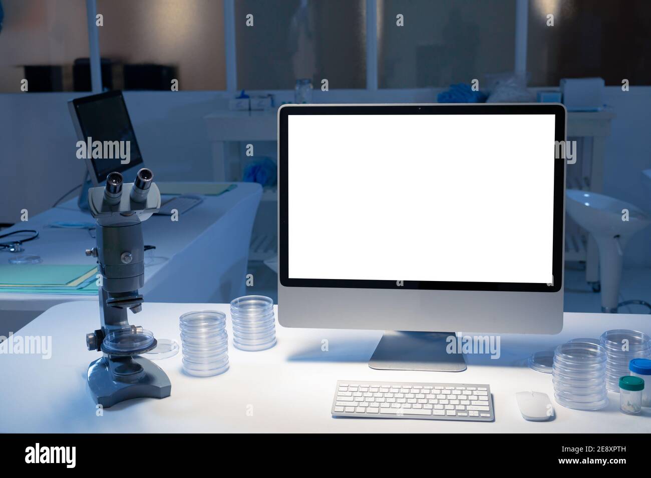 Desktop-Computer mit beleuchtetem Bildschirm am Arbeitsplatz im medizinischen Labor. Gesundheitswesen und medizinische Forschungstechnik. Stockfoto