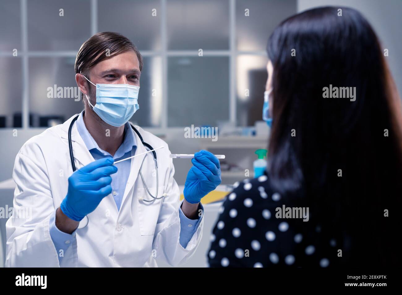 Kaukasischen männlichen Arzt trägt Gesichtsmaske und Handschuhe Vorbereitung dna Abstrich des Patienten Stockfoto