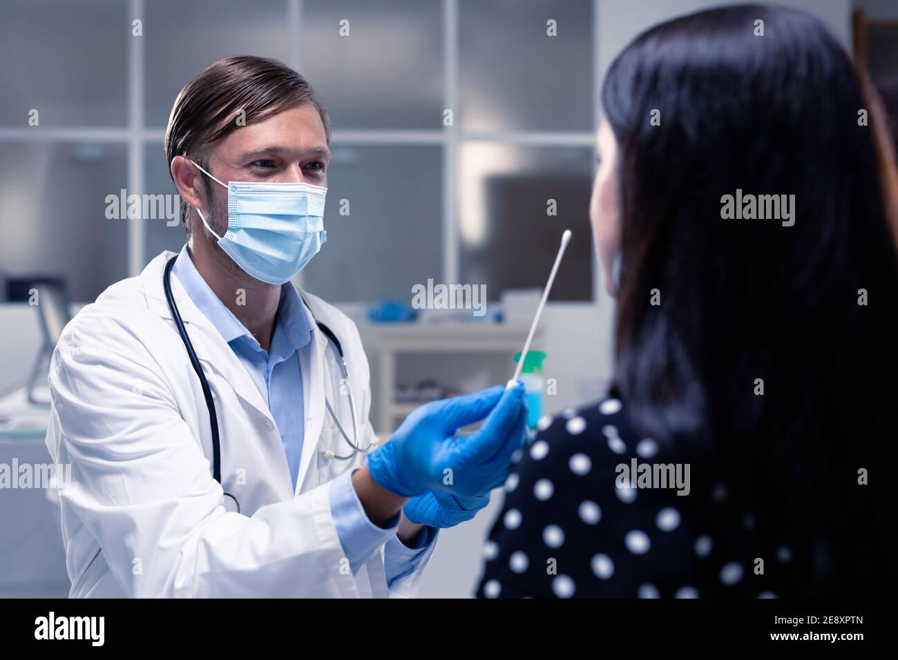 Kaukasischen männlichen Arzt trägt Gesichtsmaske und Handschuhe, die DNA Abstrich des Patienten Stockfoto