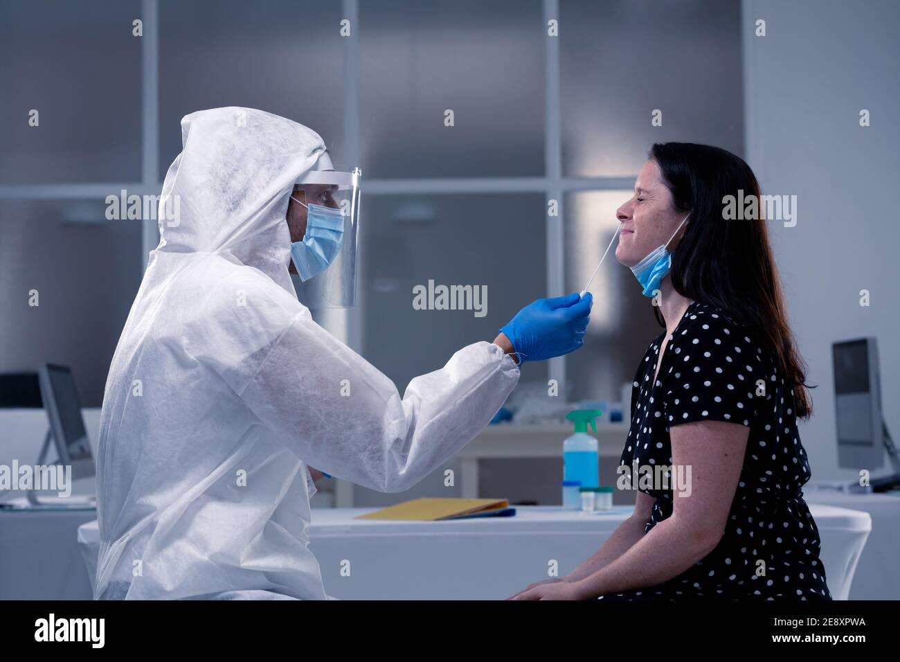 Kaukasischen männlichen medizinischen Arbeiter trägt Schutzkleidung unter Abstrich Maskierte Patientin Stockfoto