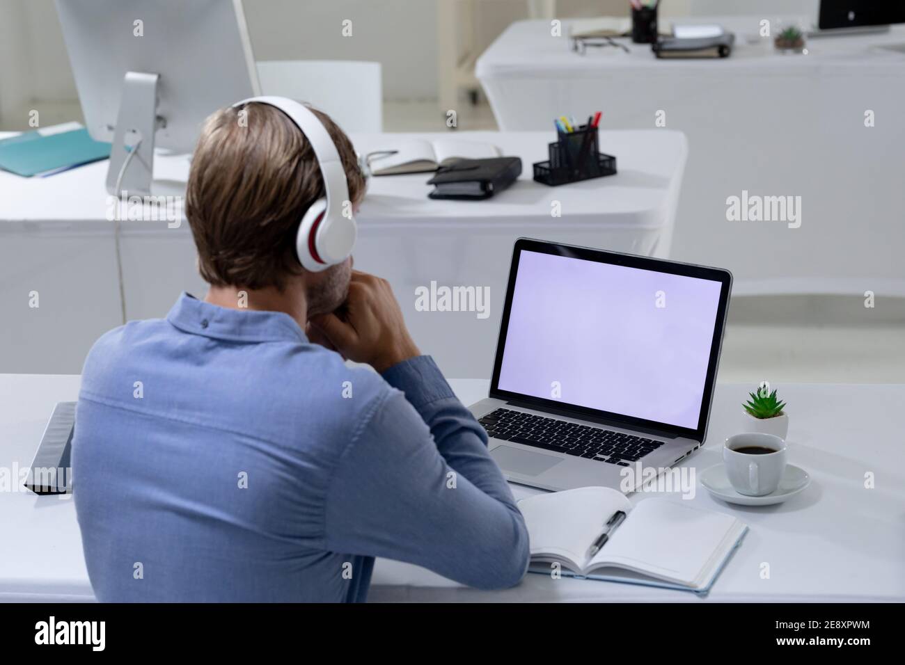Kaukasischer Geschäftsmann mit Videokonferenz mit Laptop und Kopfhörer In leerem Büro Stockfoto