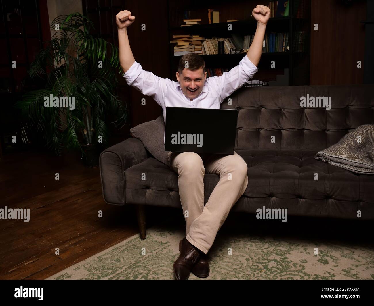 Ein Mann zu Hause schaut auf einen Laptop und freut sich über den Sieg. Online-Glücksspiel. Stockfoto