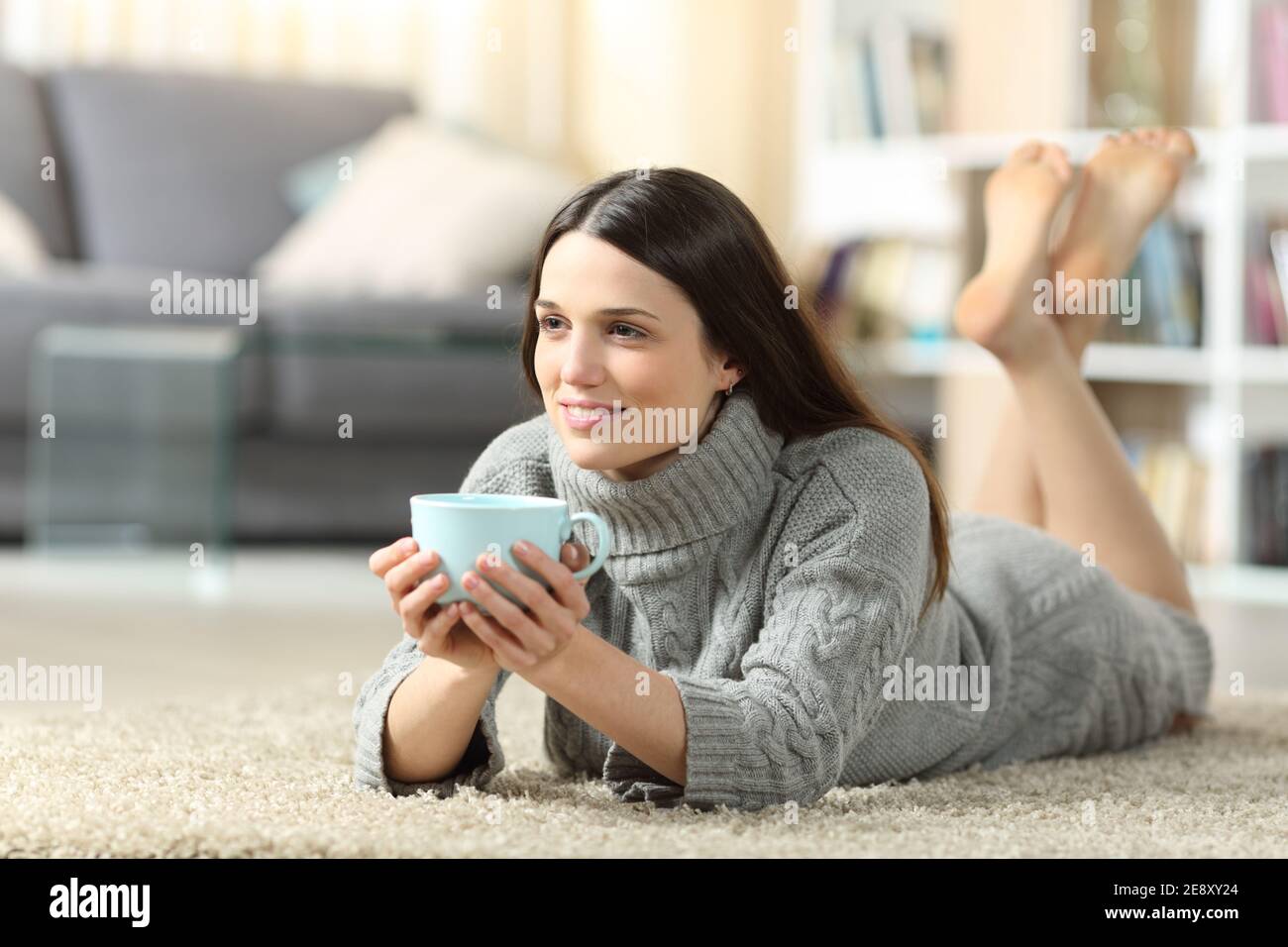 Ganzkörperportrait einer entspannten Frau, die Kaffee trinkt Haus liegt auf dem Boden Stockfoto