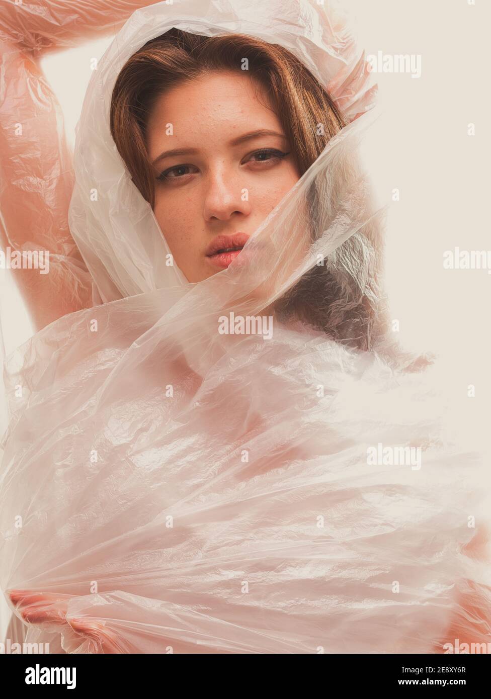 Gelber Effekt, Porträt der jungen Frau Oberkörper in Plastikfolie. Weißer Hintergrund im Studio erschossen. Stockfoto