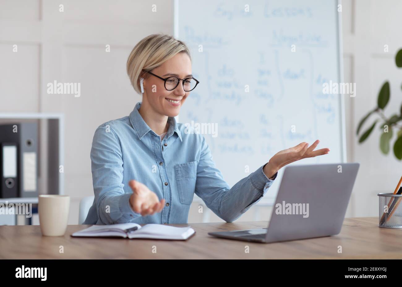 Erfahrene Englischlehrerin, die Online-Unterricht auf dem Laptop gibt, mit Schülern chattet, von zu Hause aus am Webinar teilnimmt Stockfoto