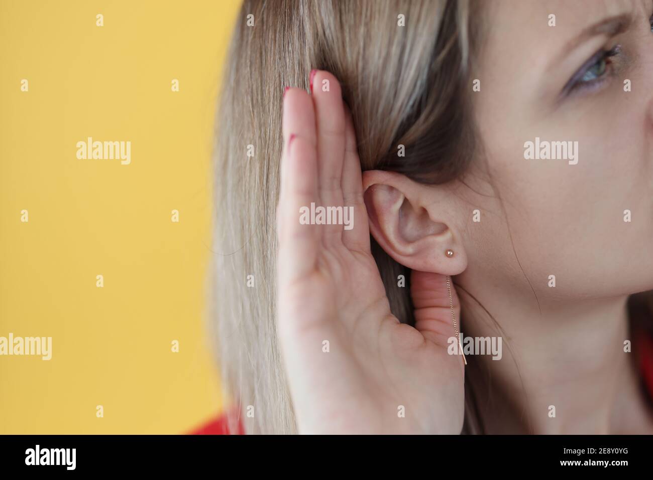 Junge hörharte Frau, die ihre Hand nahe dem Ohr hält Stockfoto