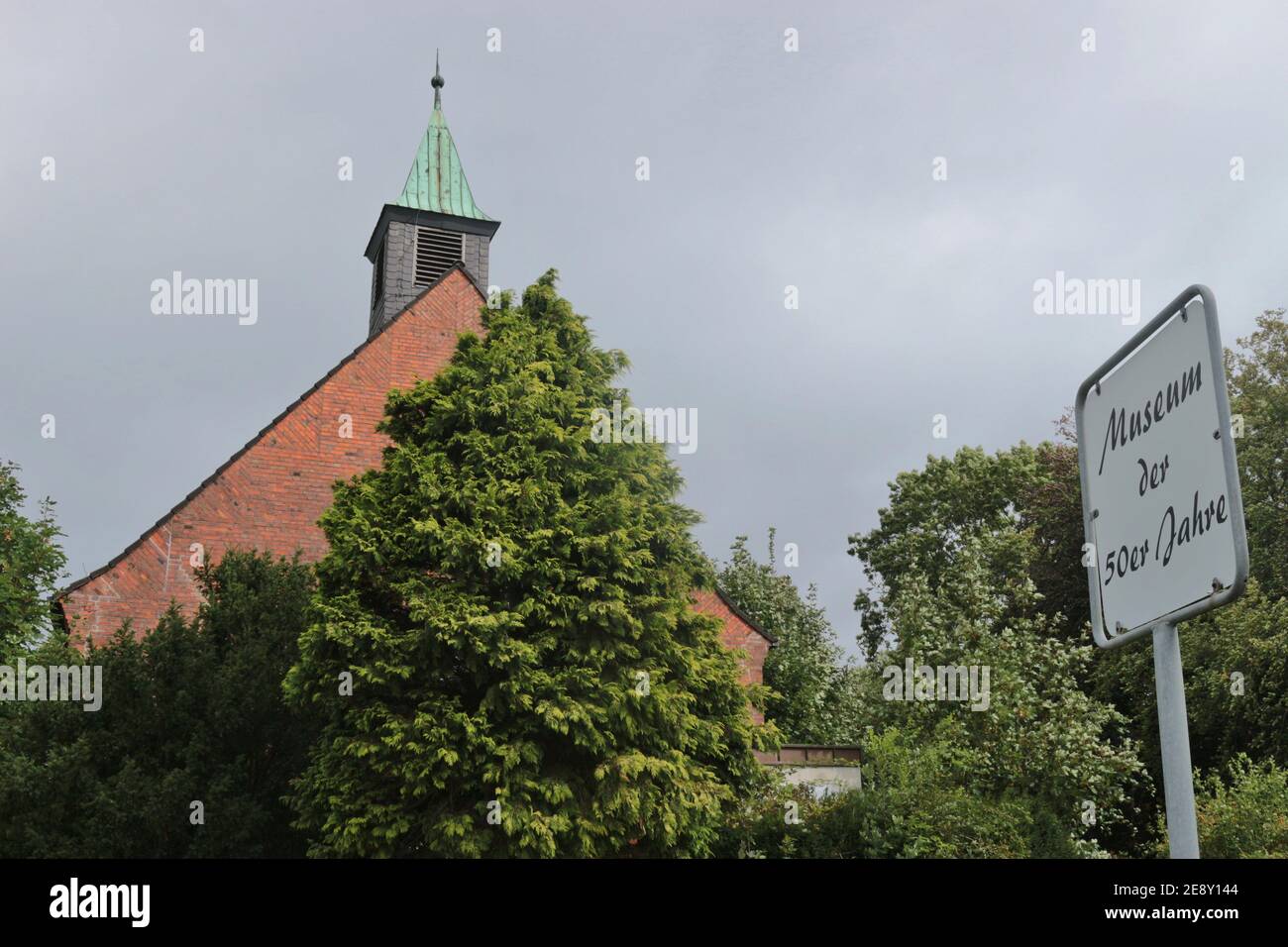 Bremerhaven: Alte Kirche und moderne Windturbine nebeneinander. Die Kirche beherbergt das Museum der 1950s im Bezirk Weddewarden. Stockfoto