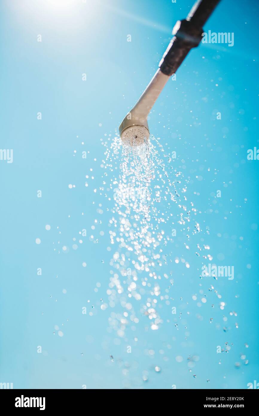 Ströme von sauberem Wasser aus einer Straße Dusche gegen ein Sonniger blauer Himmel - sommerliche Frische und ein Gefühl von Kühle in der Hitze Stockfoto