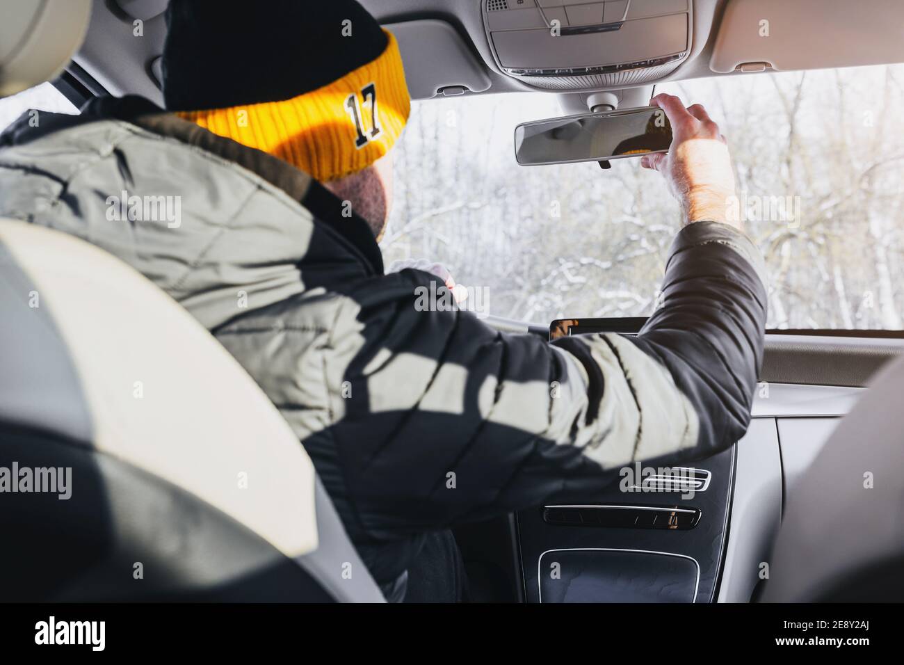 Ein Mann in Winterkleidung stellt den Spiegel in der ein Auto - Winterurlaub in der Kälte Stockfoto