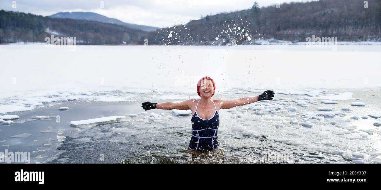 Vorderansicht der aktiven älteren Frau im Badeanzug im Freien im Wasser im Winter, Kalttherapie-Konzept. Stockfoto
