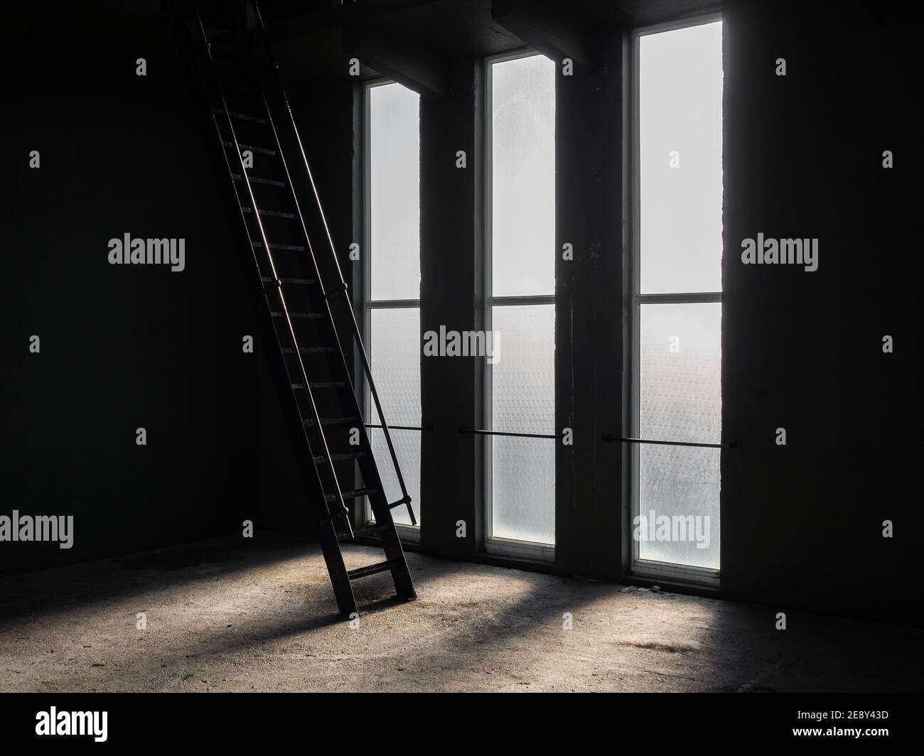Metallleitern Silhouette gegen hohe helle Glasfenster gehen nach oben In das Dach des Zimmers im dunklen alten Gebäude Schatten auf Der Boden gibt ein gruseliges unheimlich Stockfoto