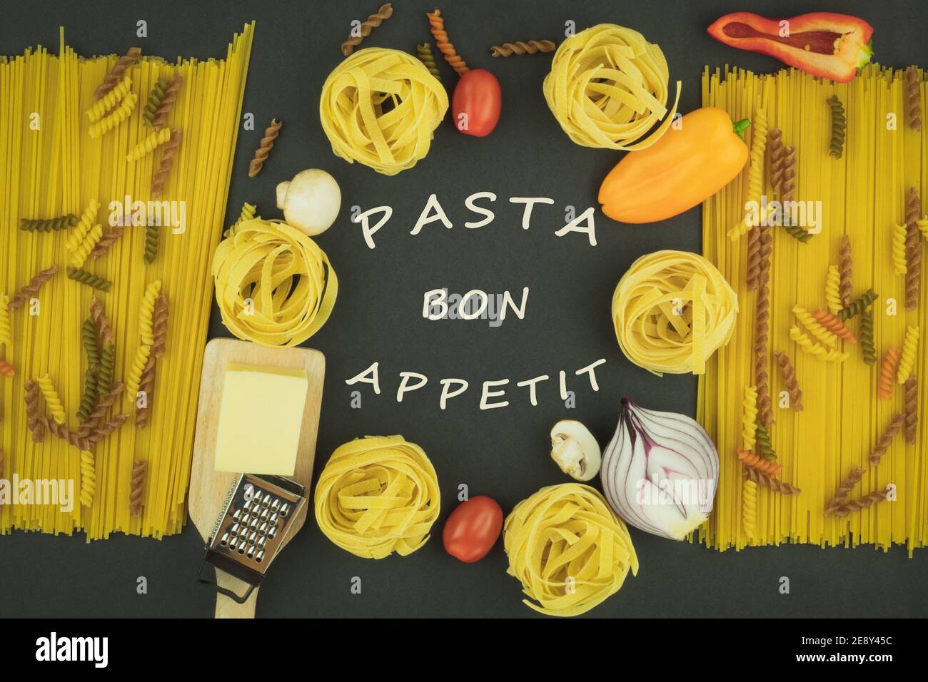 Hausgemachte Eiernudeln auf dem Tisch als Hintergrund mit Platz für Text. Das Wort Pasta wird mit dem Finger auf das Mehl geschrieben. Makkaroni mit Tomaten Stockfoto