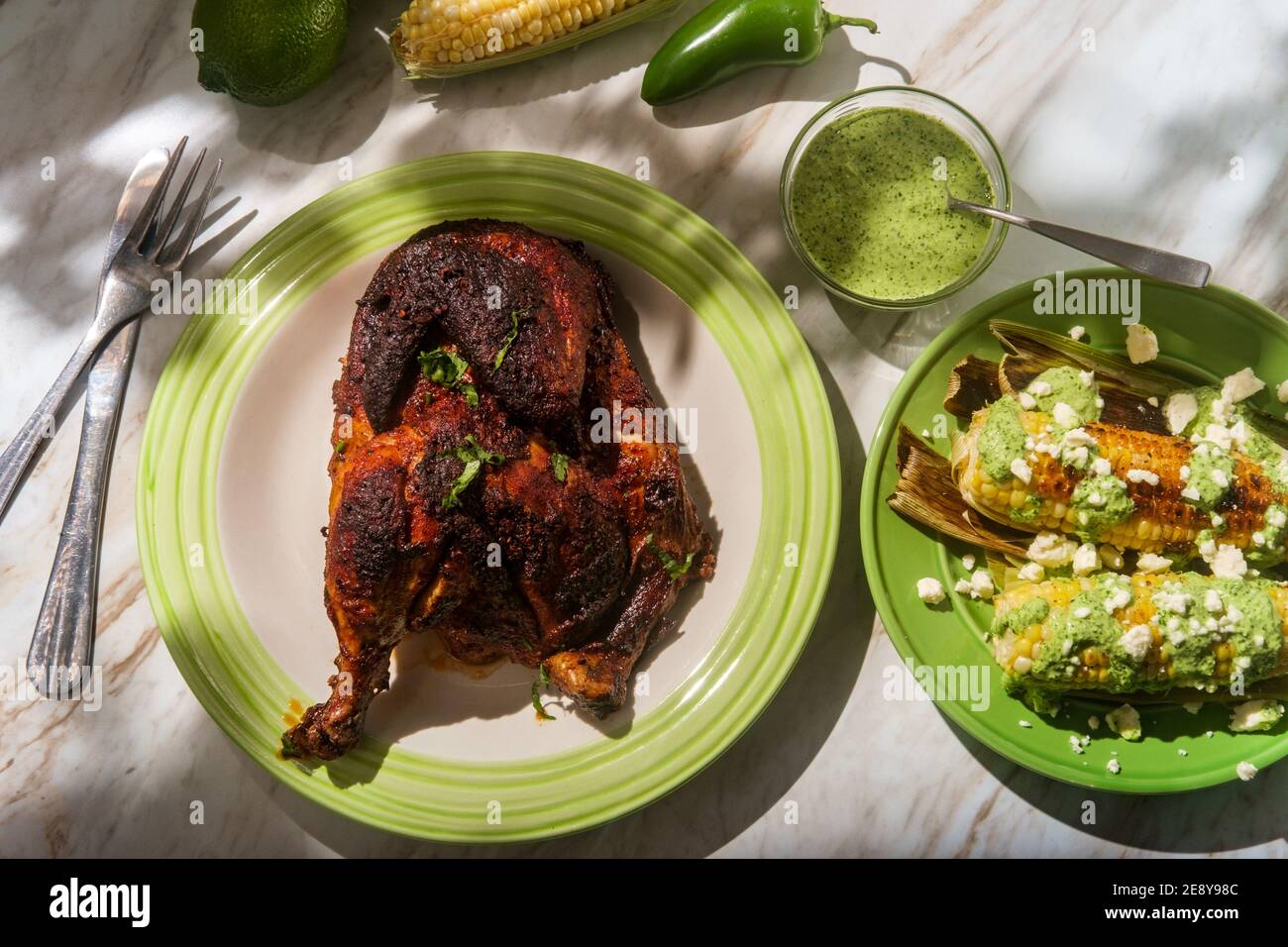 Peruanisch gebratenes halbes Huhn pollo a la brasa mit Straße Mais und grüne Sauce Stockfoto