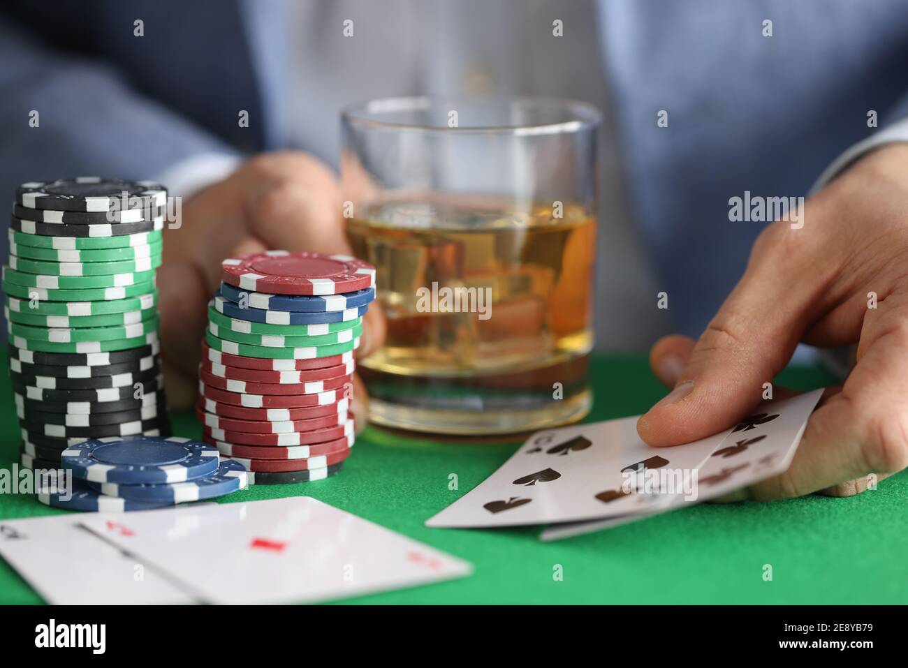 Männliche Hände halten Glas Whiskey und spielen Karten in kasino in der Nähe Stockfoto