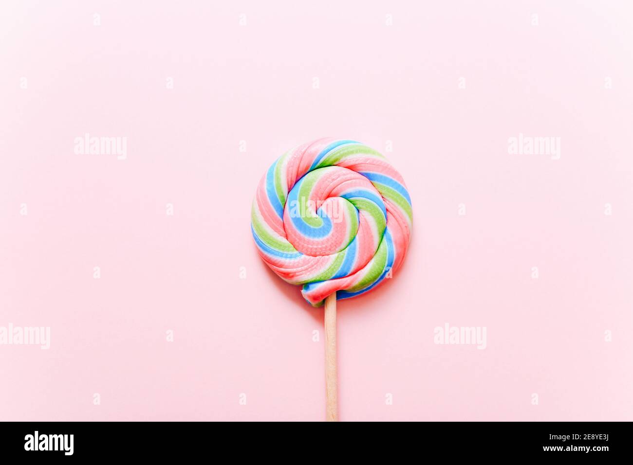 Bunte Lollipop wirbeln auf Stock. Gestreifte Spirale mehrfarbige Süßigkeiten auf rosa Hintergrund, Draufsicht Stockfoto