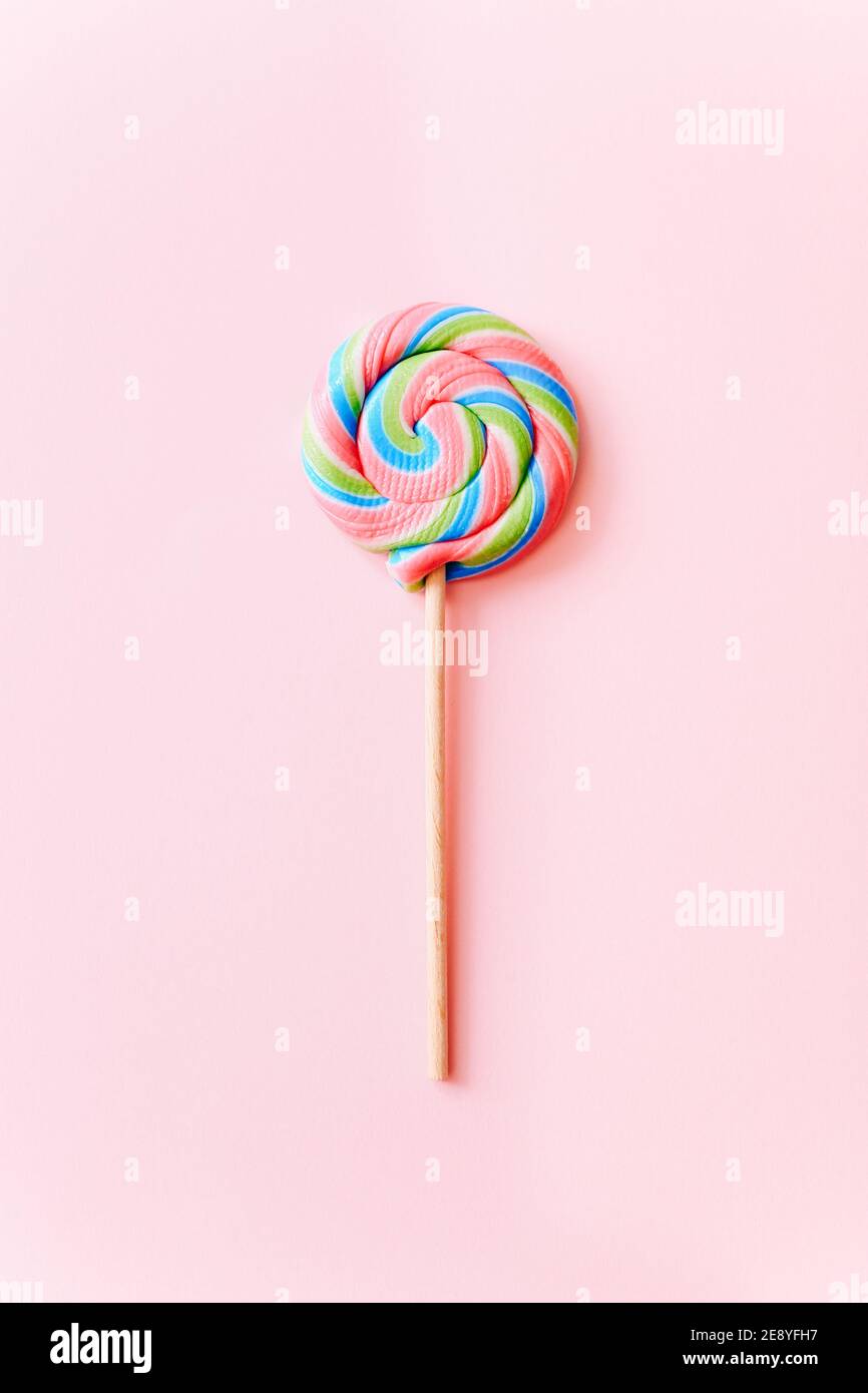 Bunte Lollipop wirbeln auf Stock. Gestreifte Spirale mehrfarbige Süßigkeiten auf rosa Hintergrund, Draufsicht Stockfoto