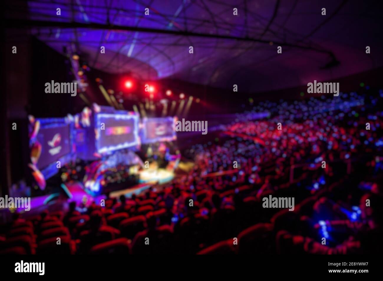 Verschwommener Hintergrund von eSports Veranstaltung in der großen Arena mit vielen Lichtern und Bildschirmen. Stockfoto