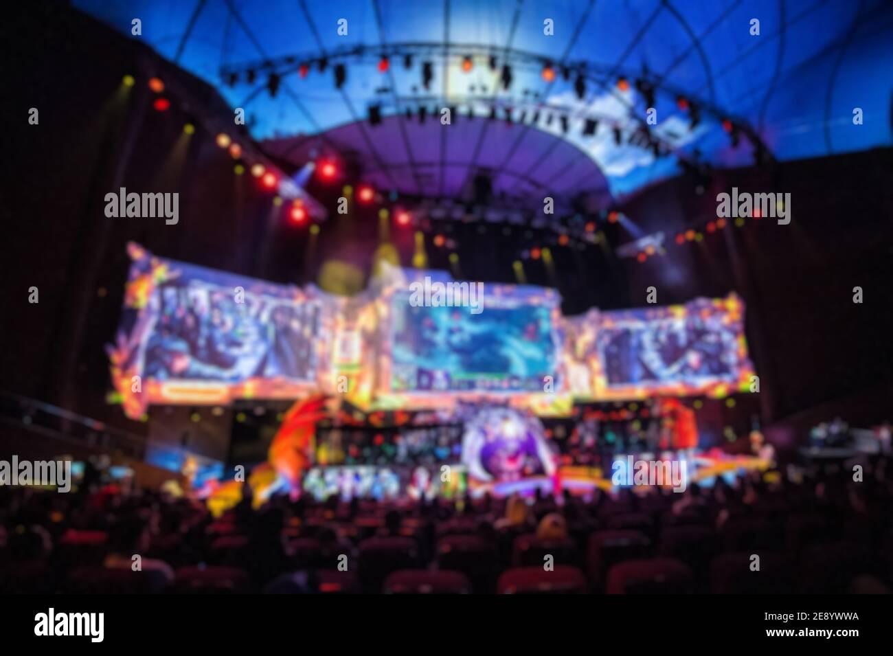 Verschwommener Hintergrund von eSports Veranstaltung in der großen Arena mit vielen Lichtern und Bildschirmen. Stockfoto