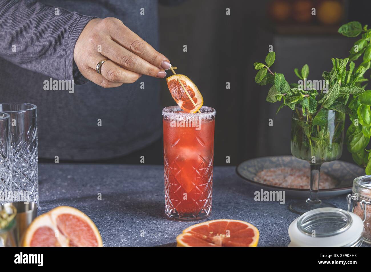 Echte Frau bereitet rosa Grapefruit Mezcal Paloma Cocktail in Highball Glas  mit Wassertropfen auf dem Tisch in Real Home. Neues Lebenskonzept der  Quarantäne Stockfotografie - Alamy
