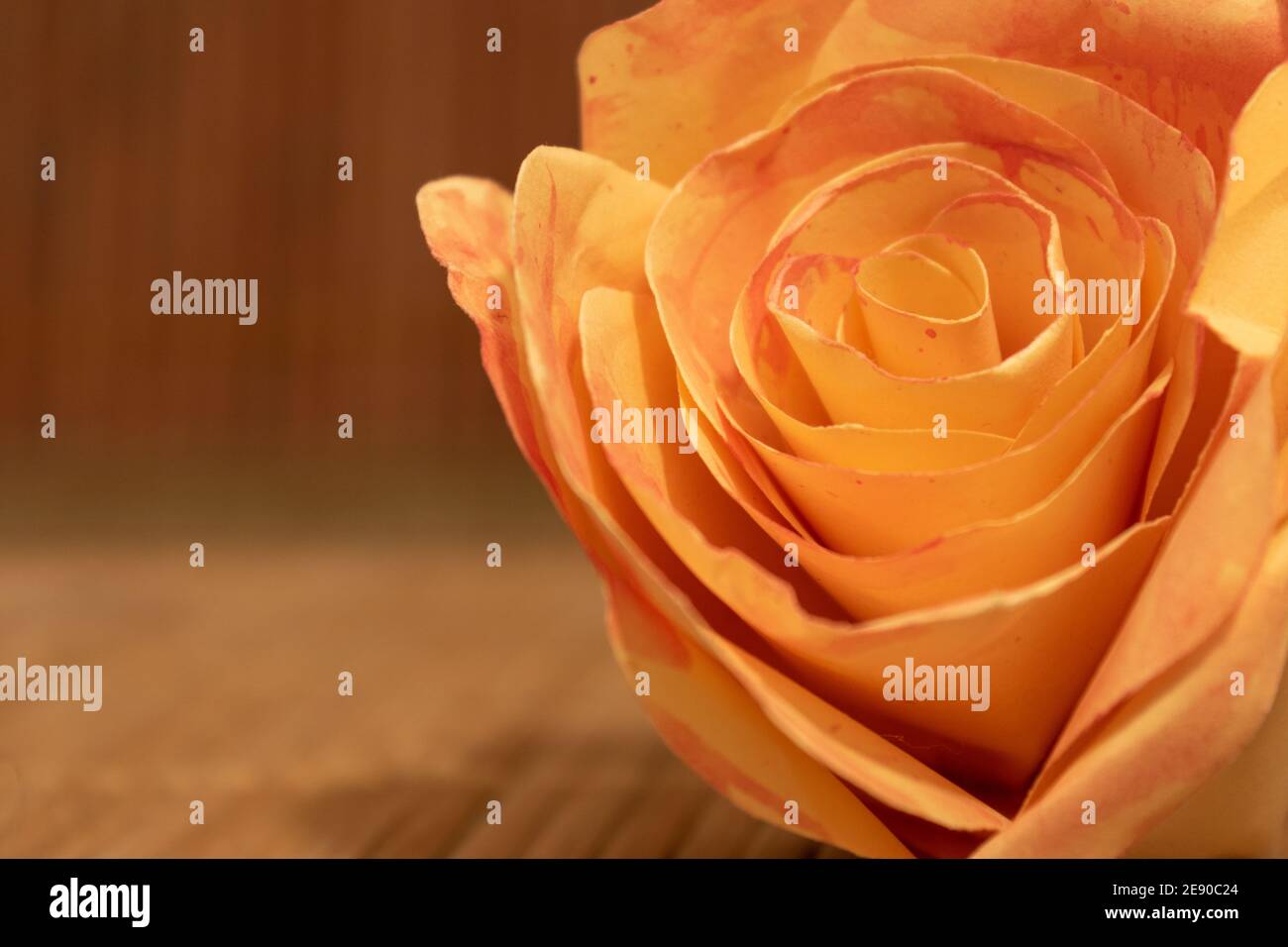 Nahaufnahme der orangen Rosenblüte aus Papier auf Holztisch liegend mit Kopieplatz. Romantisches Konzept Stockfoto