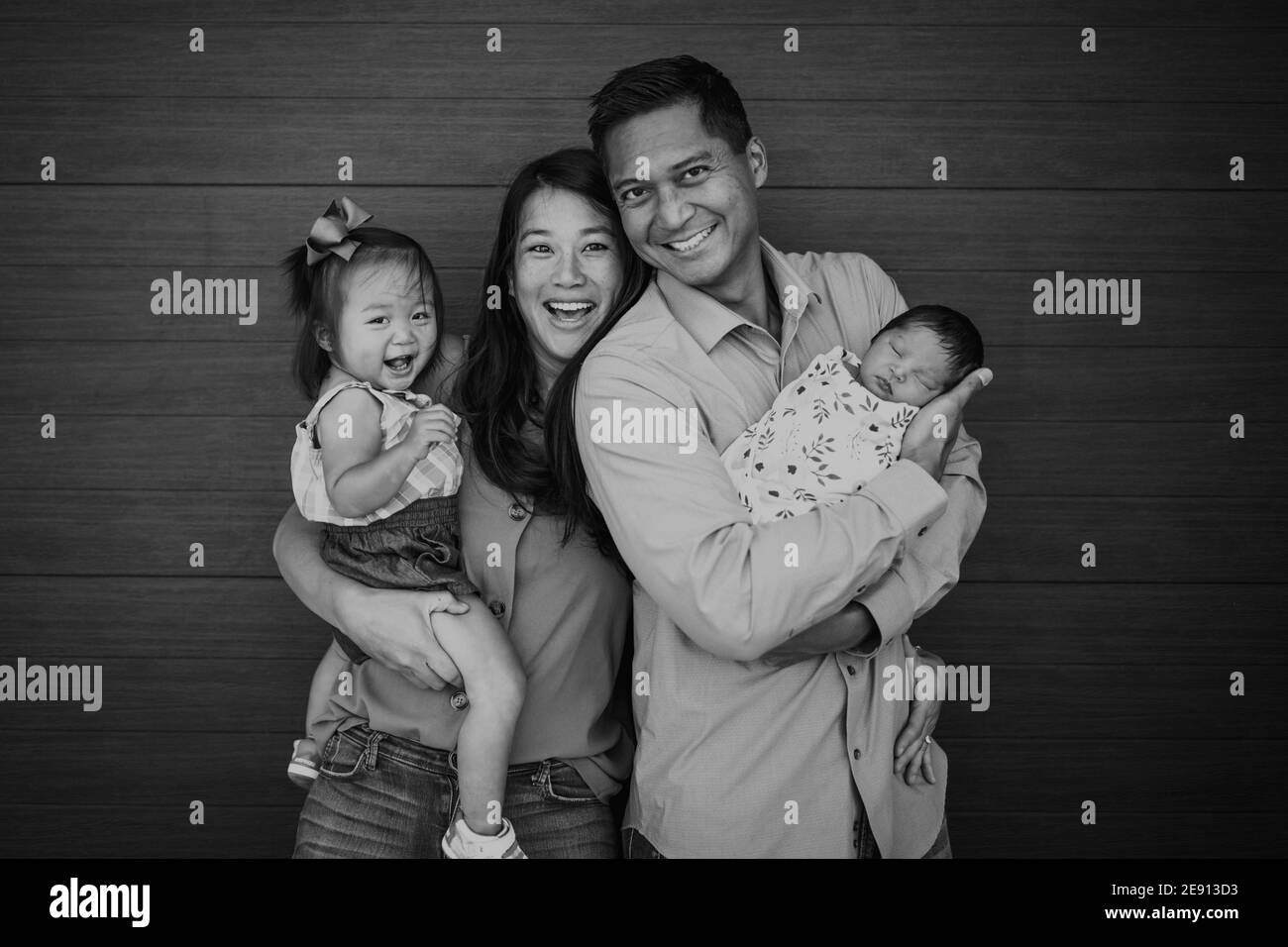 Glückliche asiatisch-amerikanische Familie mit jungen Mädchen und schlafen neugeborenes Stockfoto