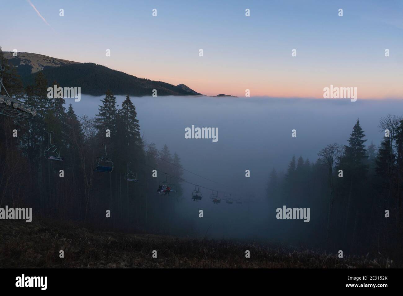 Sessellift für Skifahrer Bewegen auf dem Gipfel bei Sonnenuntergang Zeit und Foggy Day im Skigebiet Bukovel, Karpaten, Ukraine Stockfoto