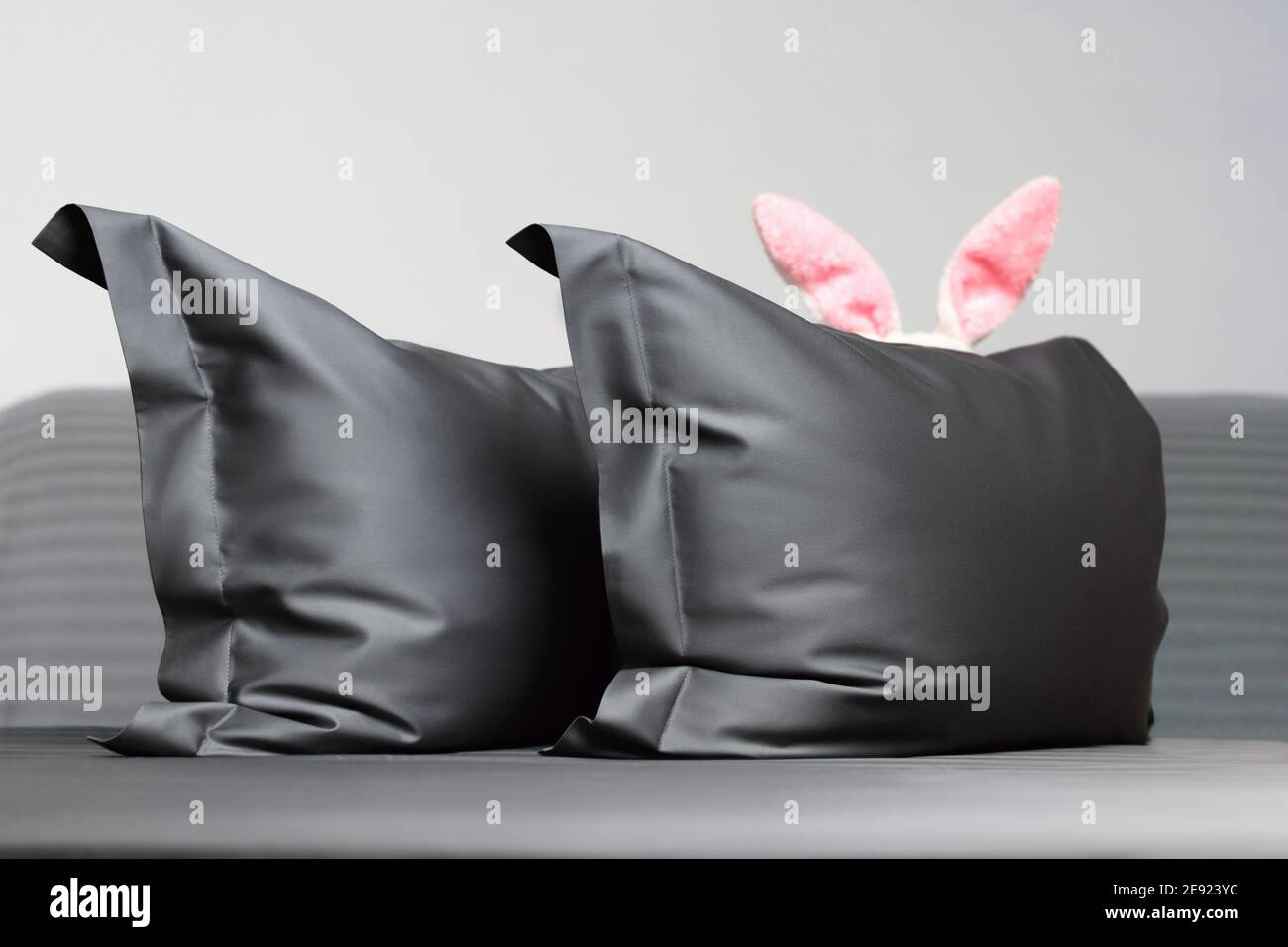 Nahaufnahme auf dem Bett zwei graue Daunenkissen mit Osterhasen-Ohren. Stockfoto