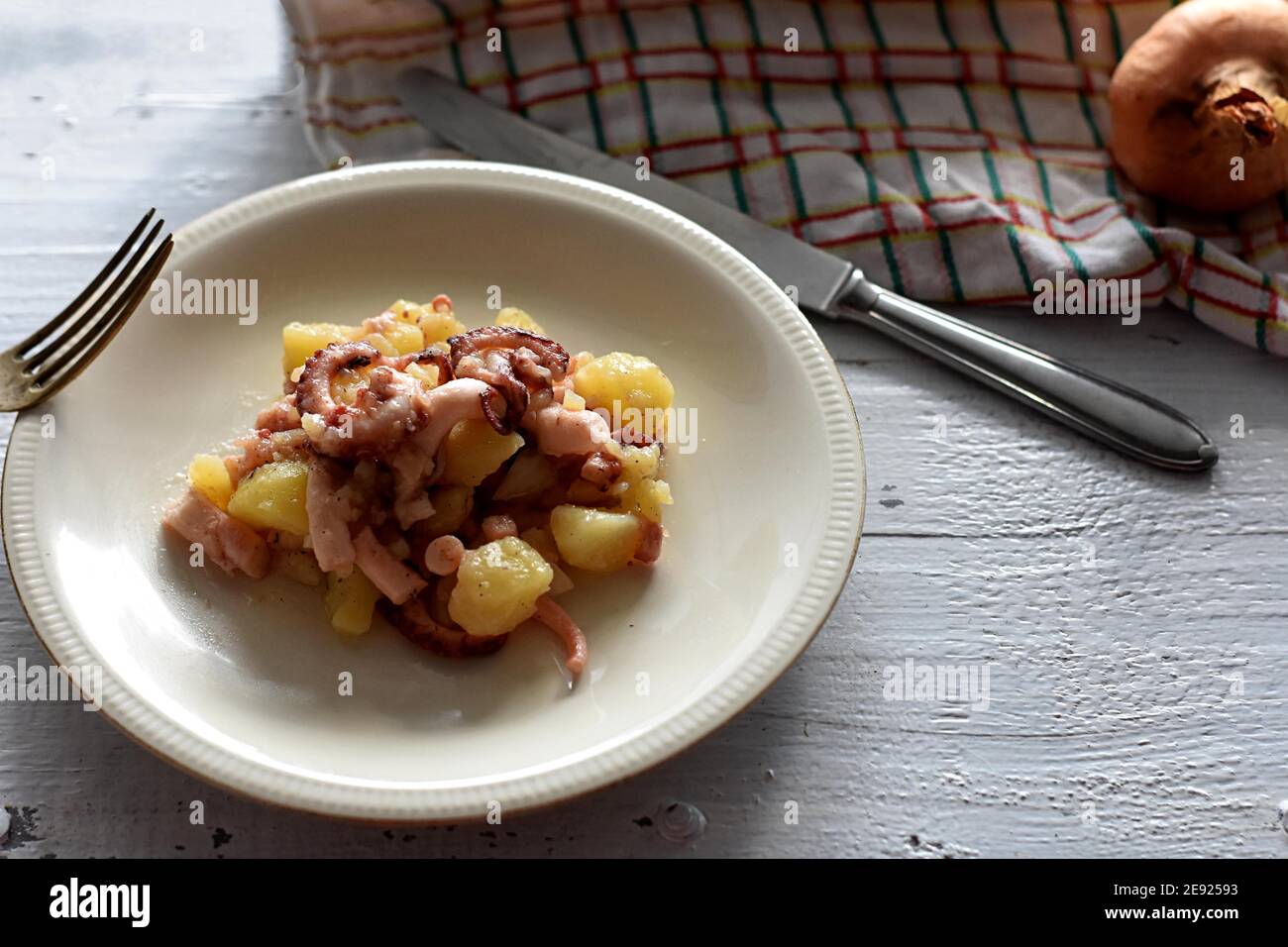 Nahaufnahme von Oktopus/Maulkorb-Salat mit Kartoffeln und Zwiebeln Weißer Teller/mediterrane gesunde Fischküche Stockfoto