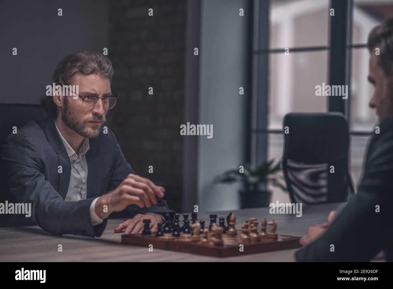 Mann mit Schachfigur, der den Gegner anschaut Stockfoto