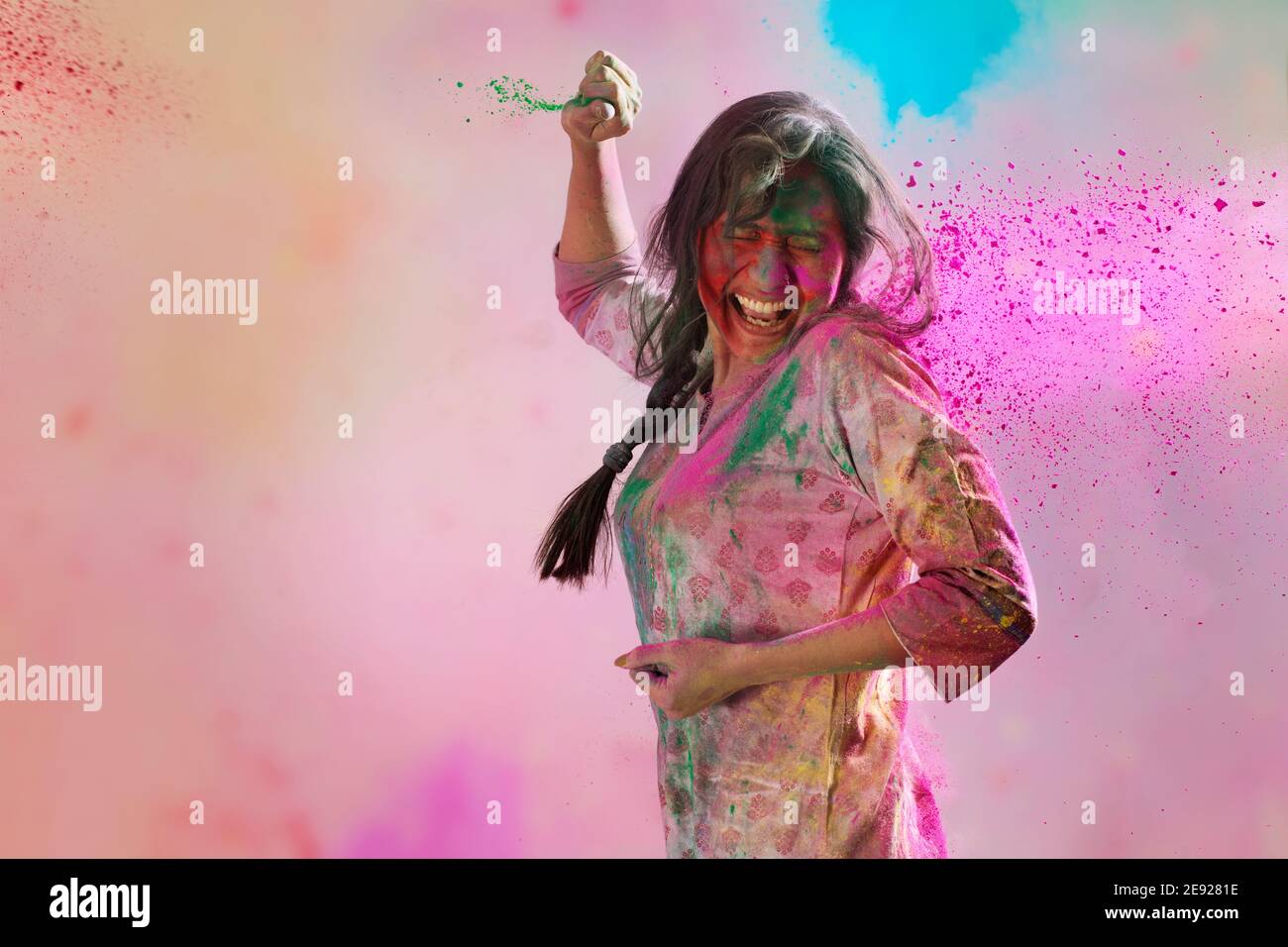 Frau mit Farben überall stehend mit geschlossenen Augen In Überraschung und Gulal in ihren Händen auf Holi Stockfoto