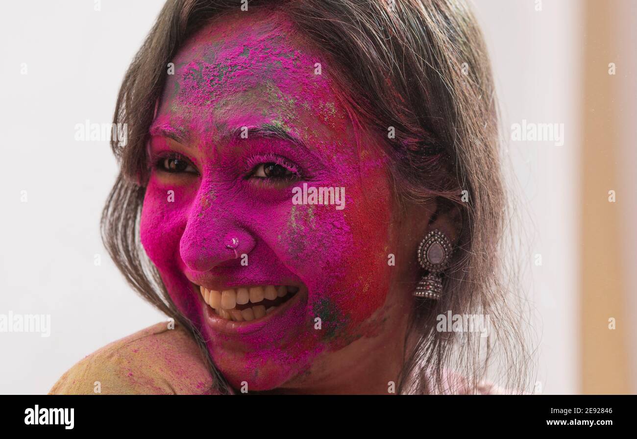 Porträt einer Frau lächelnd mit rosa Gulal auf ihr Gesicht Stockfoto