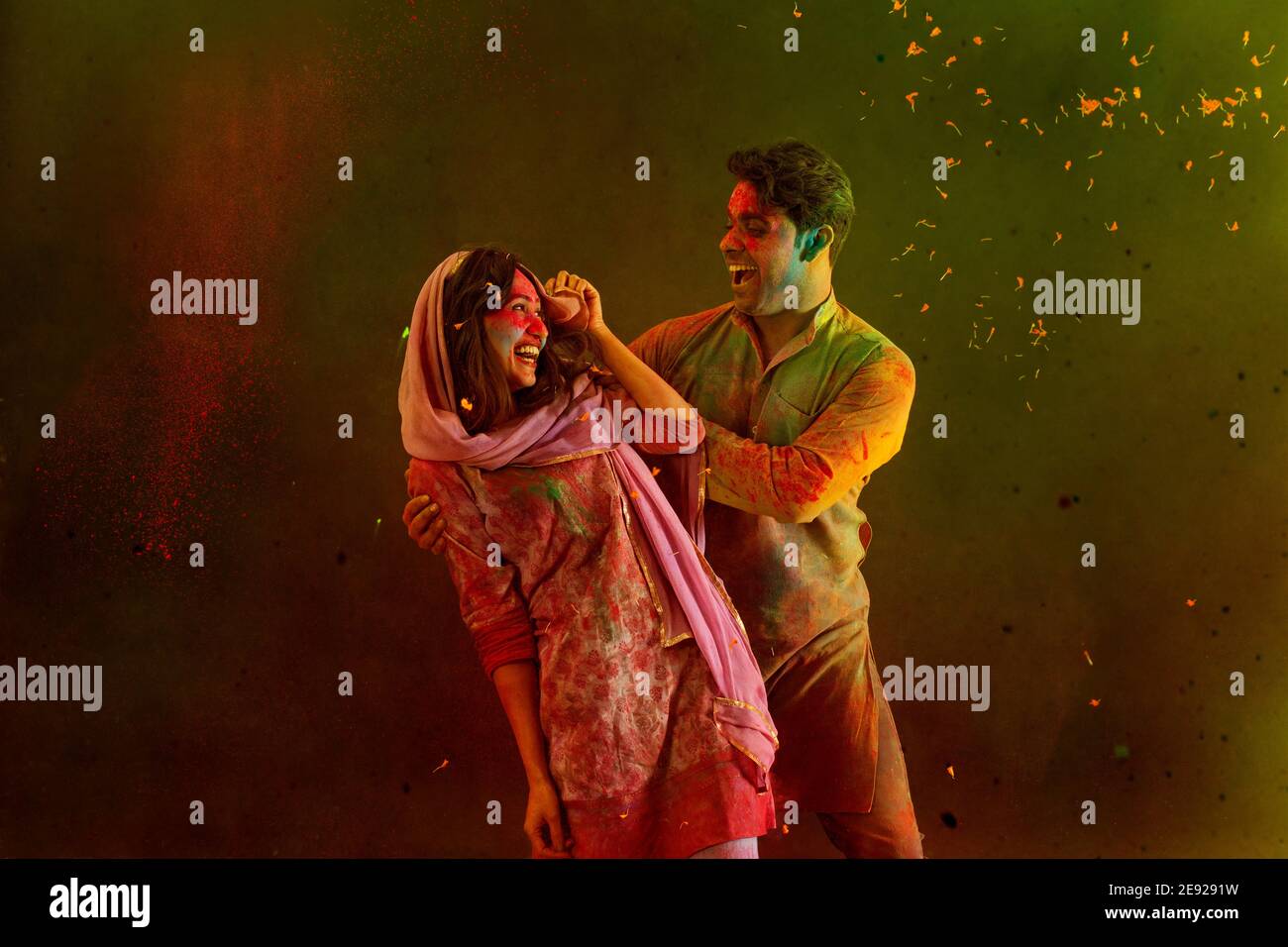 Ehemann und Ehefrau tanzen, während sie Holi mit trockenen Farben feiern Stockfoto