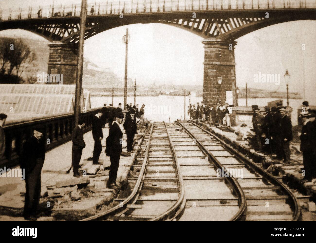 Ein altes Foto aus Scarborough, North Yorkshire, Großbritannien, zeigt die neu angelegten Straßenbahnschienen unter der Valley Bridge mit Arbeitern, Aufsehern und Beobachtern, die sich für ein Foto des fertiggestellten Abschnitts versammeln. Scarborough Bay und Hafen sind im Hintergrund zu sehen. Baubeginn war am 12th. Oktober 1903 (Eröffnung am 6th. Mai 1904) Stockfoto