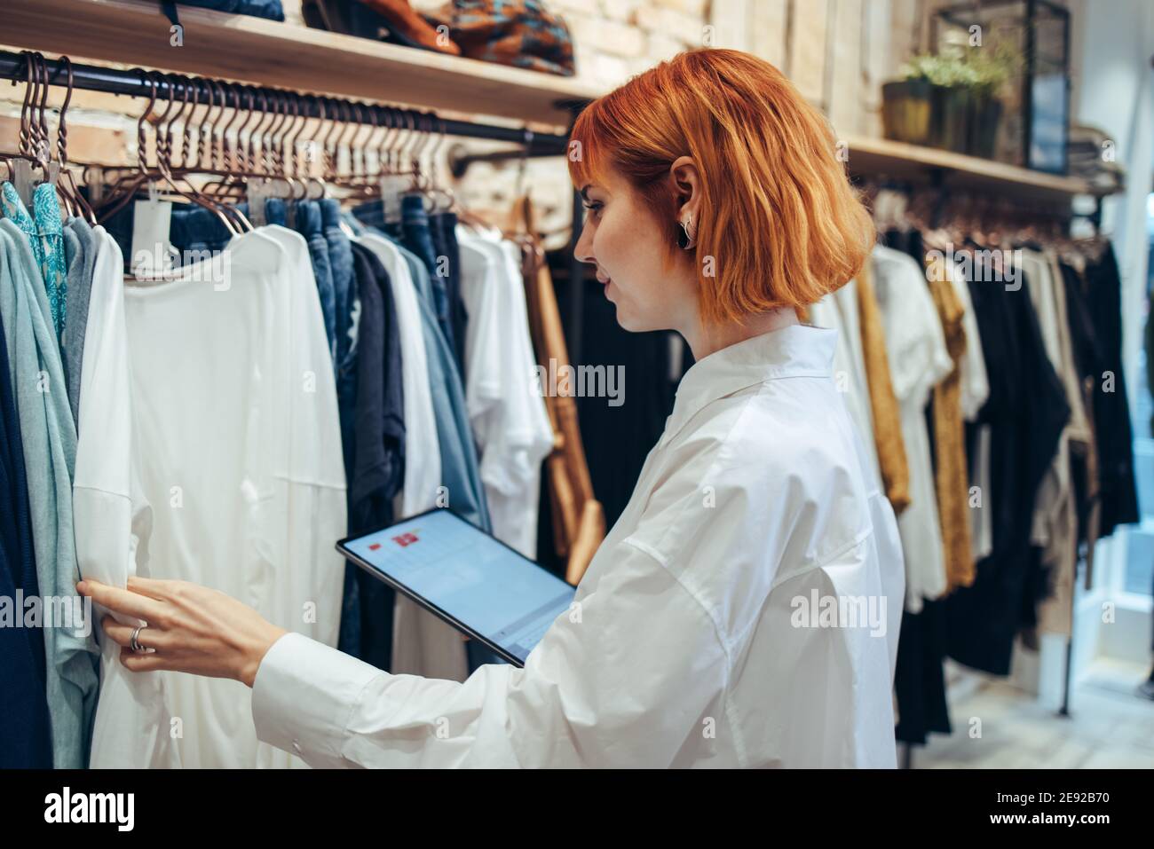 Frau nimmt Inventar auf digitalen Tablet im Bekleidungsgeschäft. Frau Managerin in einem Modehandel mit einem Tablet für die Arbeit und Überprüfung der Shop s Stockfoto