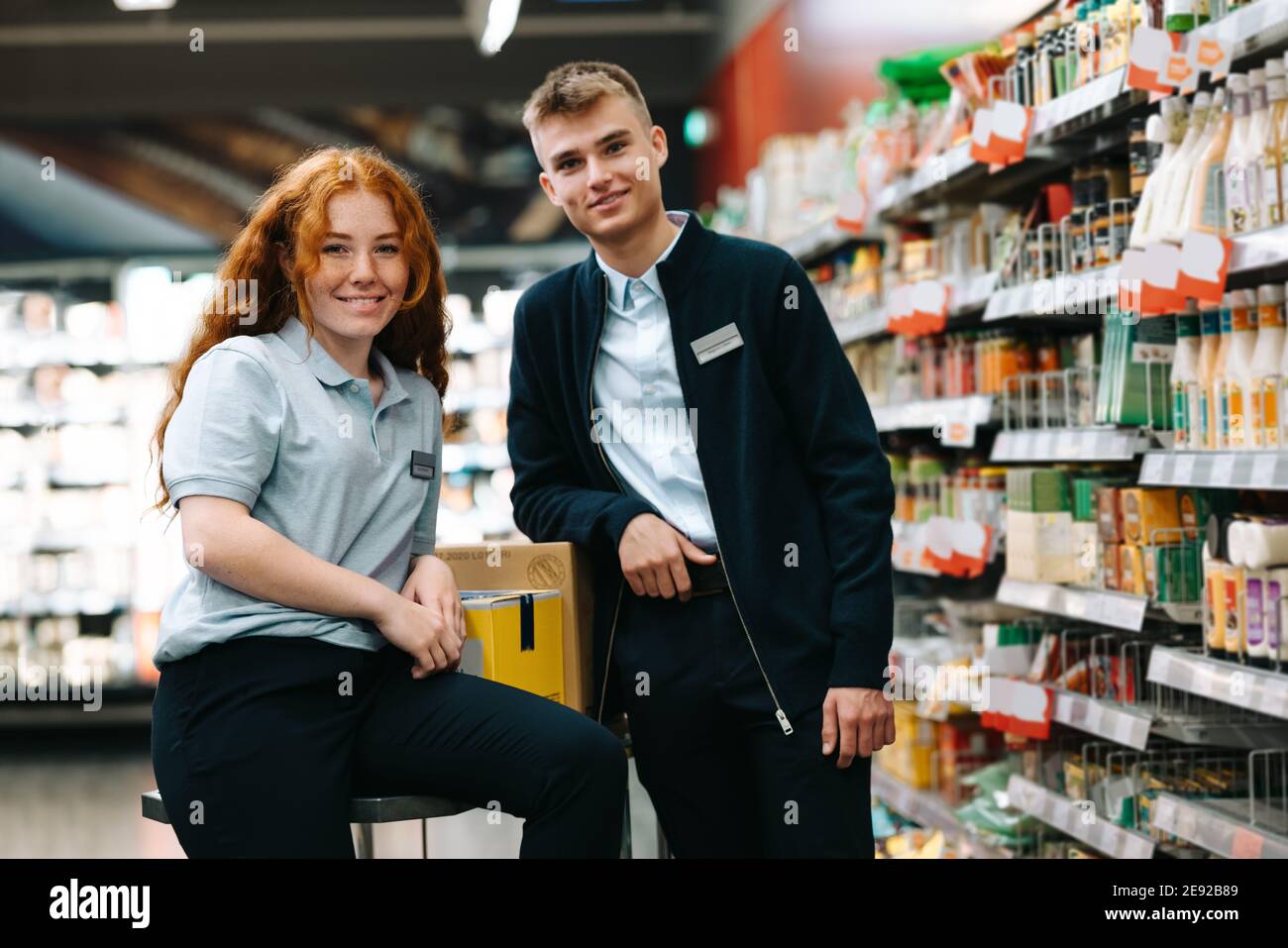 Porträt von zwei Supermarktarbeitern. Junge und Mädchen auf Urlaub Job in lokalen Lebensmittelgeschäft. Stockfoto