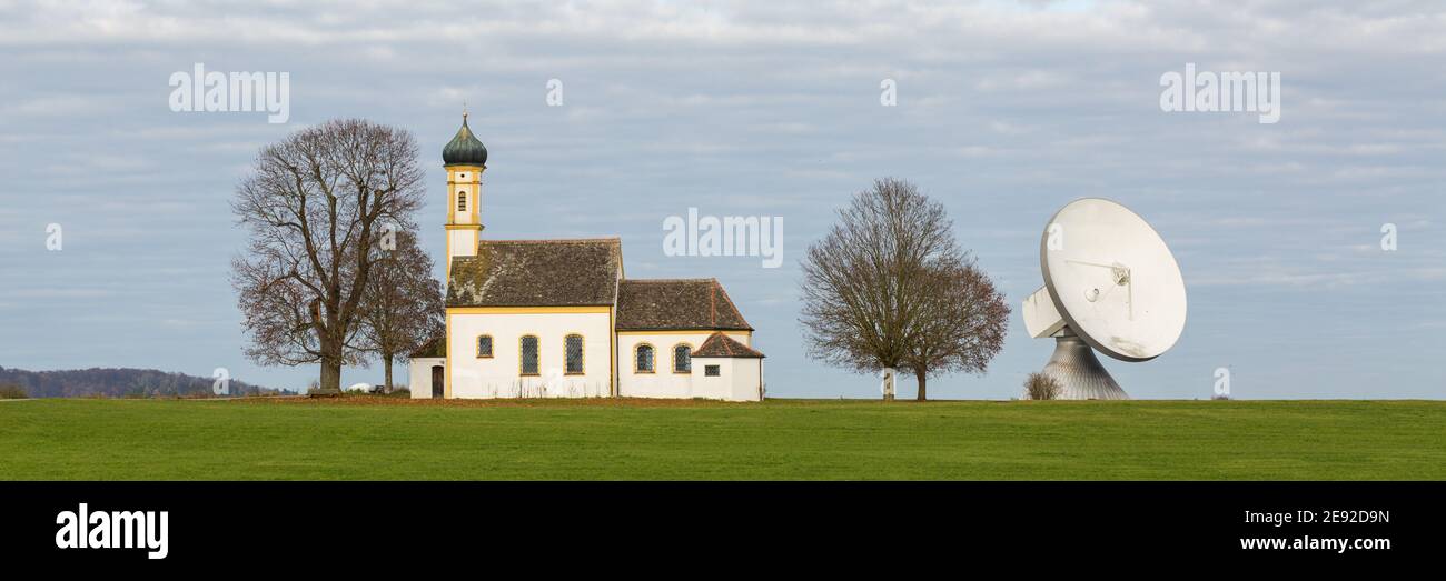 Raisting, Deutschland - 13. Nov 2020: Panorama mit einer Kirche und einer Satellitenschüssel (Radom). Symbiose aus Tradition und Technik. Stockfoto