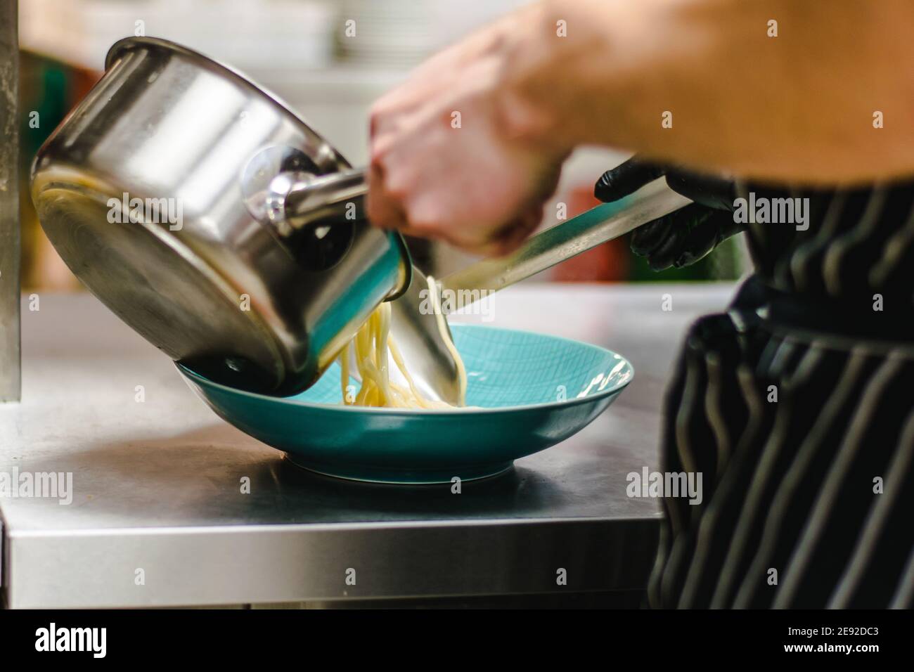 Küchenchef bereitet Ramen-Nudelsuppe mit Fleisch, Eiern und Gemüse in einem Restaurant zu Stockfoto