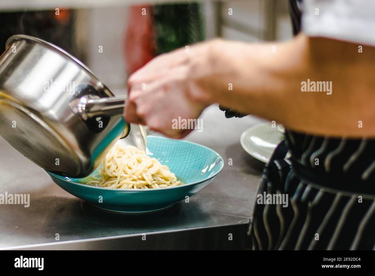 Küchenchef bereitet Ramen-Nudelsuppe mit Fleisch, Eiern und Gemüse in einem Restaurant zu Stockfoto