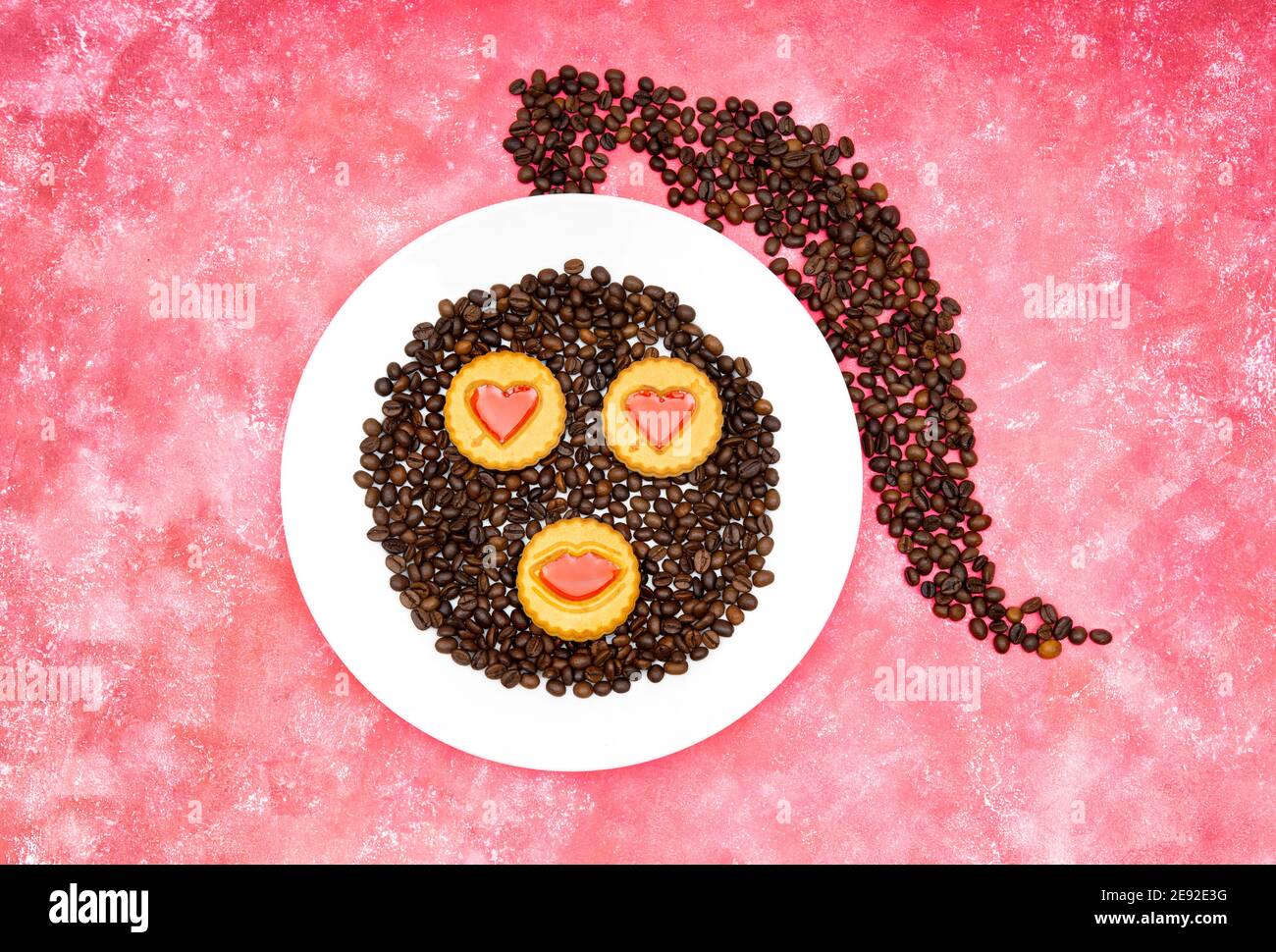 Frauengesicht aus gerösteten Kaffeebohnen und dekorierten Keksen Auf einem rosa Hintergrund Stockfoto