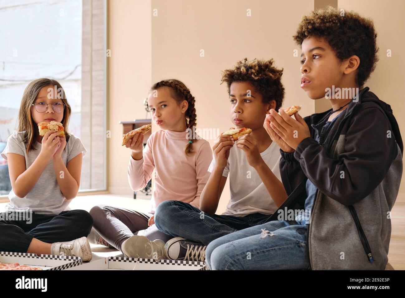 Gruppe von niedlichen multi Rasse Kinder kleine Jungen Mädchen sitzen  drinnen essen Pizza italienische Fast-Food-Küche. Alpha-Generierung teilt  Slices, verbringt Zeit miteinander Stockfotografie - Alamy