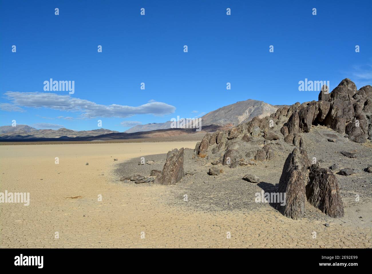 Die Tribüne auf der Rennstrecke Playa im Death Valley National Park, ein sehr dunkelgrauer Felsen, umgeben von unerschütterlichem, hellem Lehmboden Stockfoto