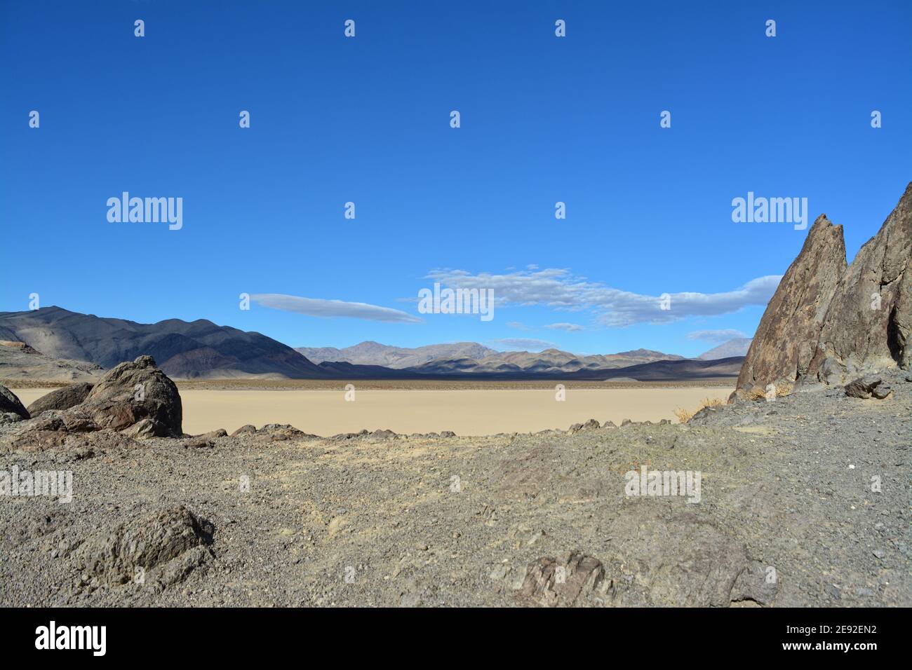 Die Tribüne auf der Rennstrecke Playa im Death Valley National Park, ein sehr dunkelgrauer Felsen, umgeben von unerschütterlichem, hellem Lehmboden Stockfoto