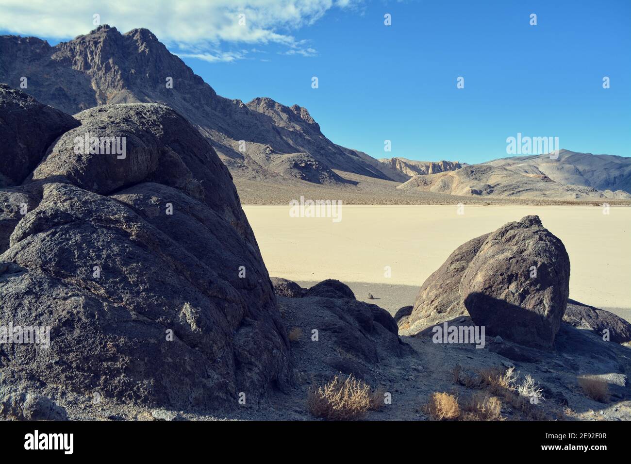 Die Tribüne auf der Rennstrecke Playa im Death Valley National Park, ein sehr dunkelgrauer Felsen, umgeben von unerschütterlichem, hellem Lehmboden Stockfoto