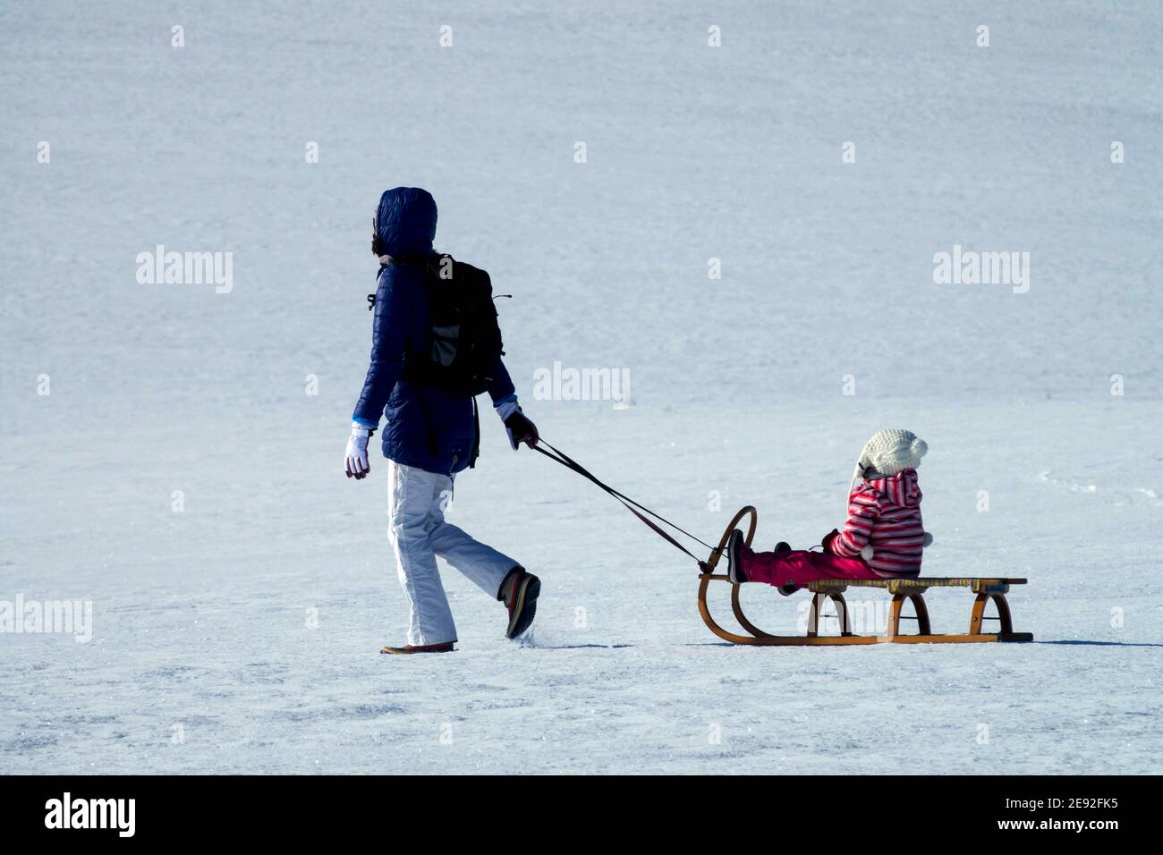 Schlittenfahren im Winter, weibliches Kind auf Schlitten, Schneelandschaft Frau und Kind Stockfoto