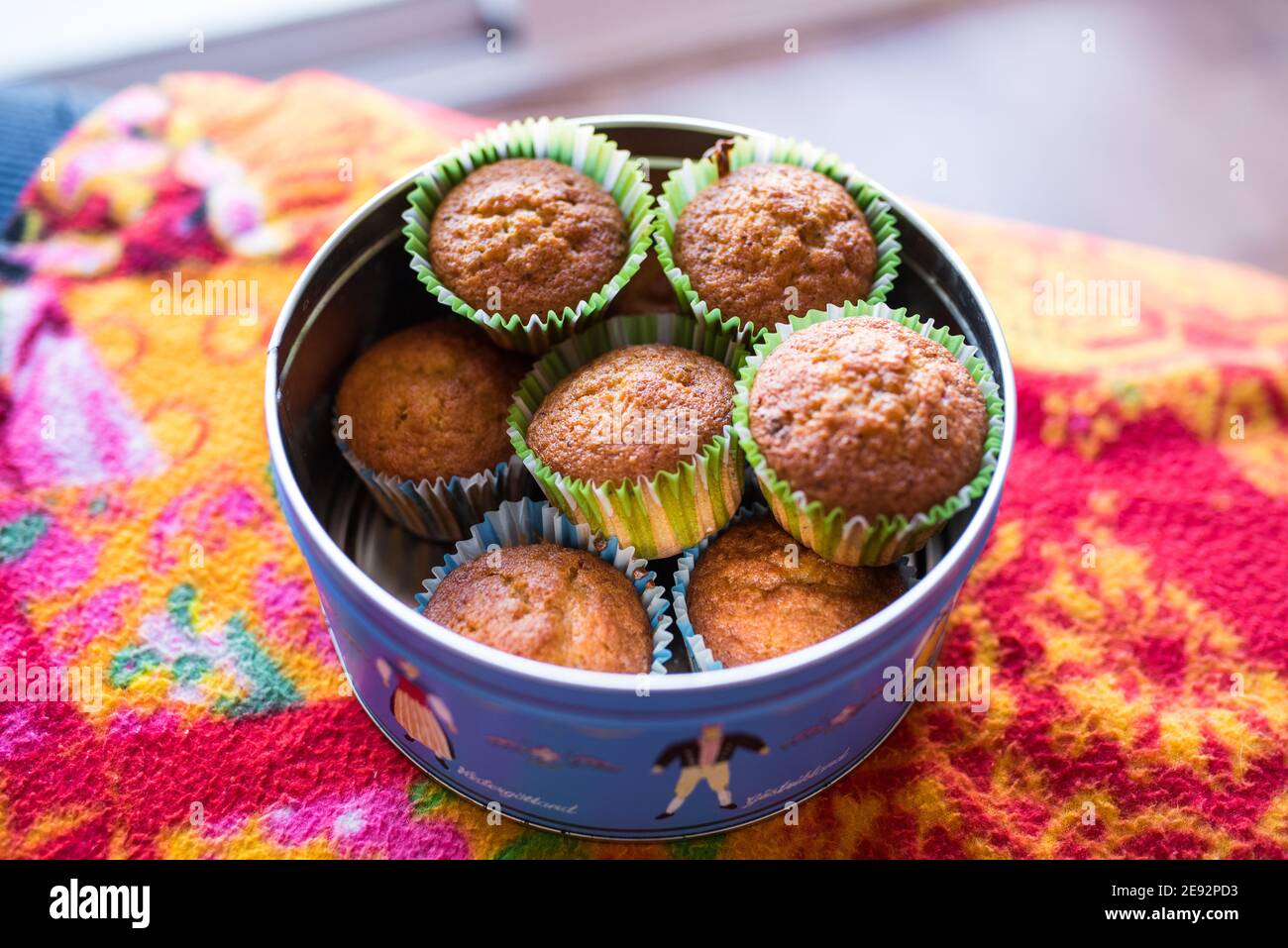 Cupcakes verpackt mit farbigen Papieren in einem blauen Metall platziert Box auf einer farbigen Decke Stockfoto