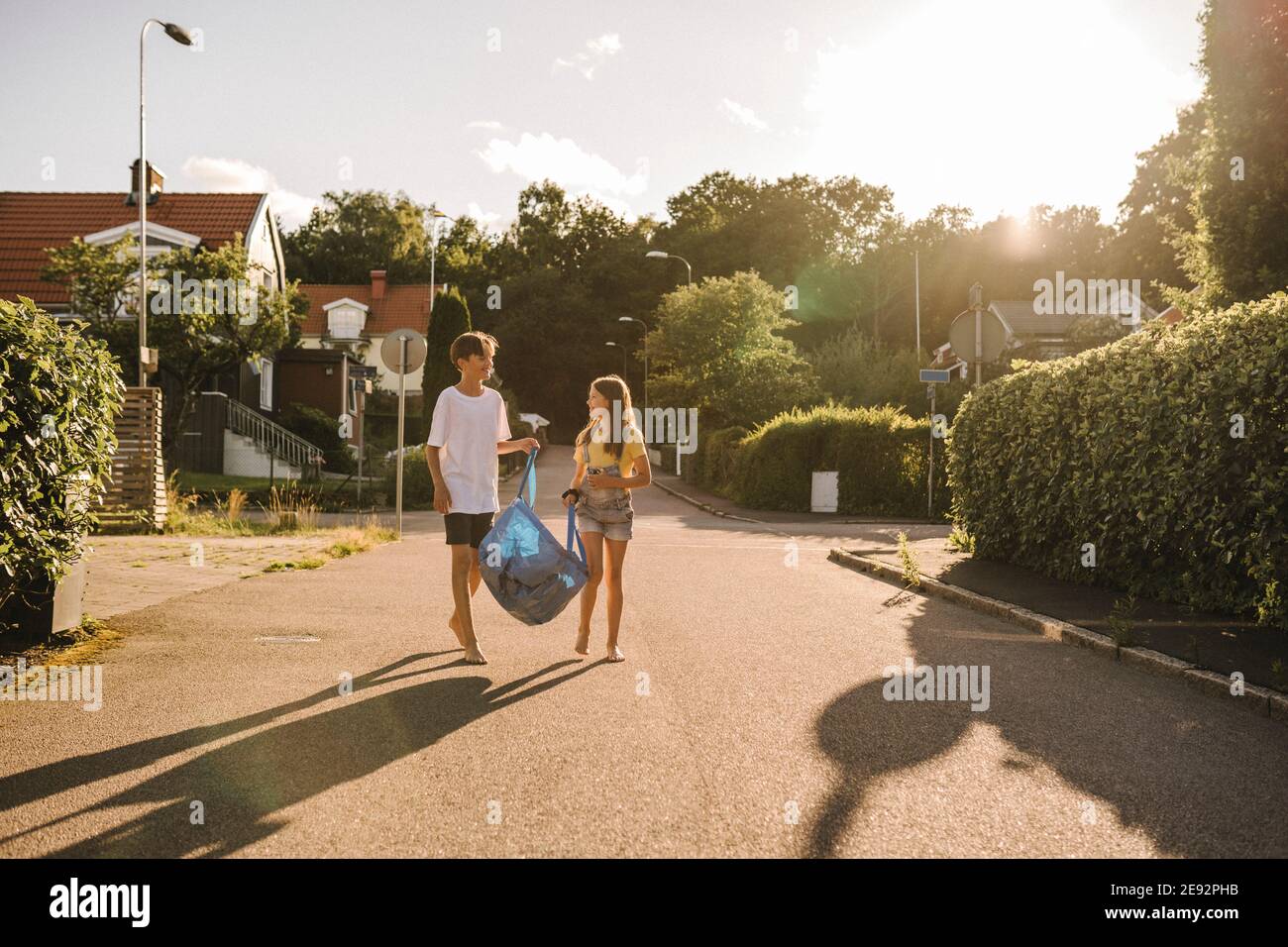 Geschwister tragen Tasche auf der Straße während sonnigen Tag Stockfoto