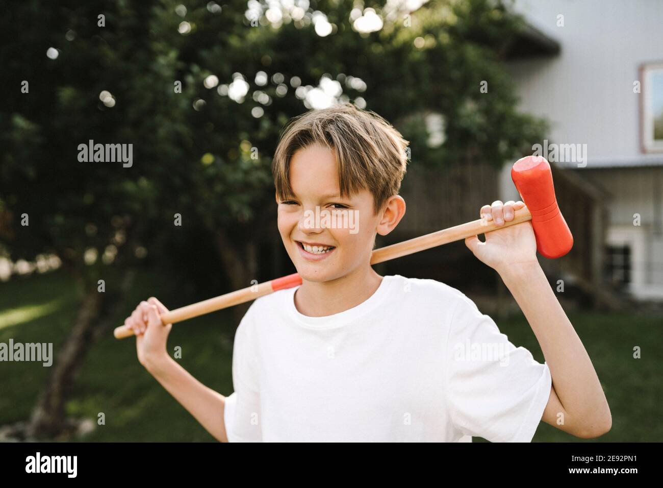 Kaukasischer Junge mit Polo-Schläger im Hinterhof Stockfoto