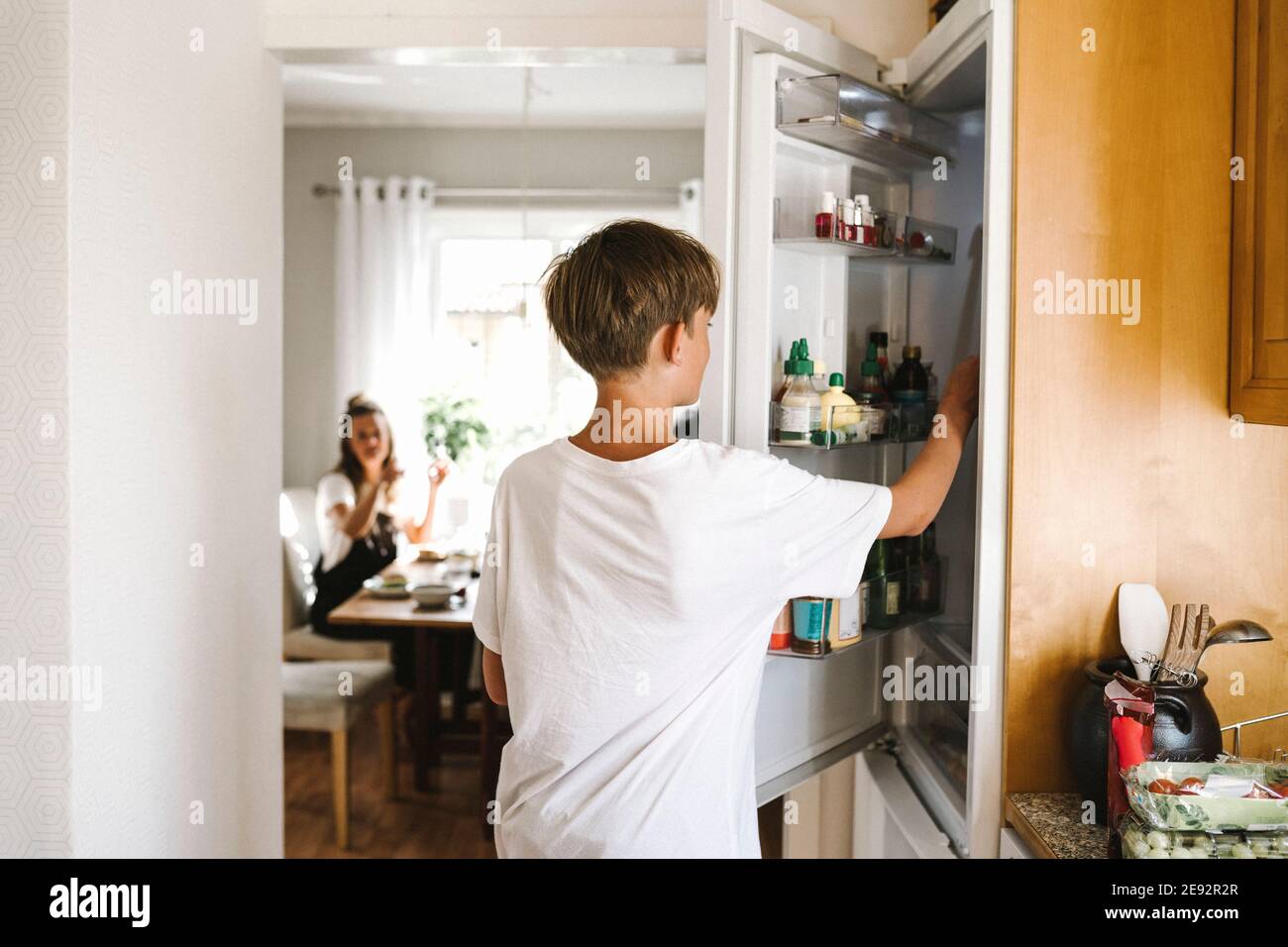 Vorpubertär Junge öffnen Kühlschranktür, während in der Küche stehen Stockfoto